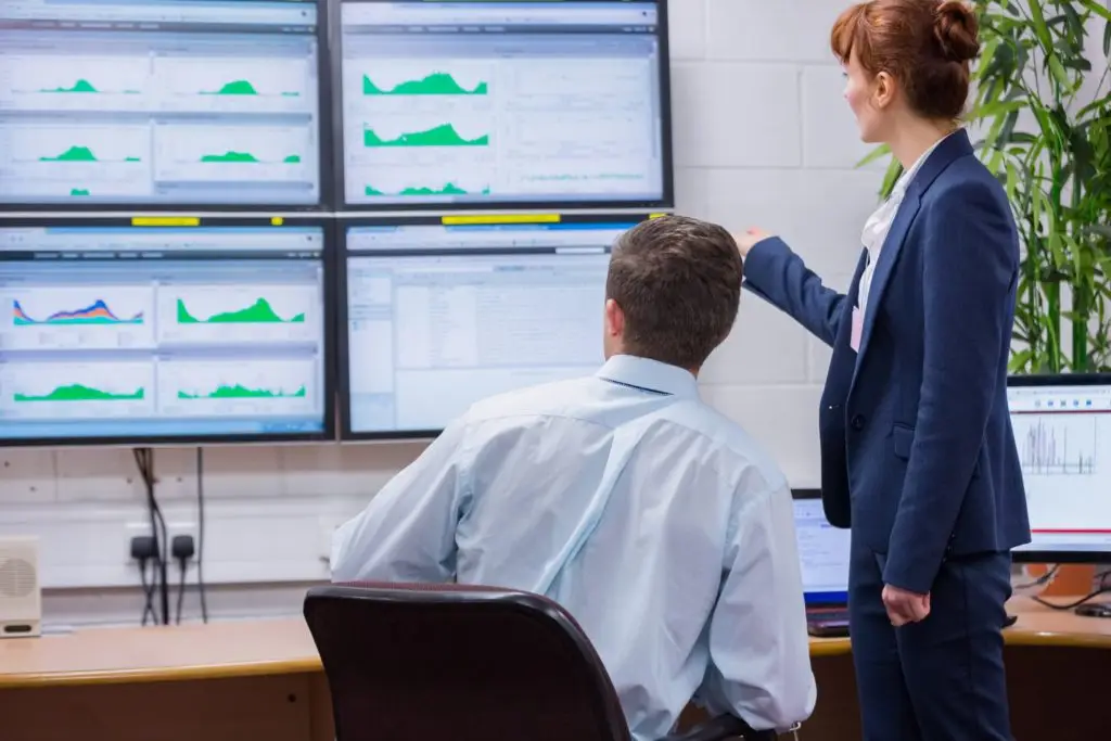 Focused colleagues analyzing result on their computer in office running diagnostics in large data center